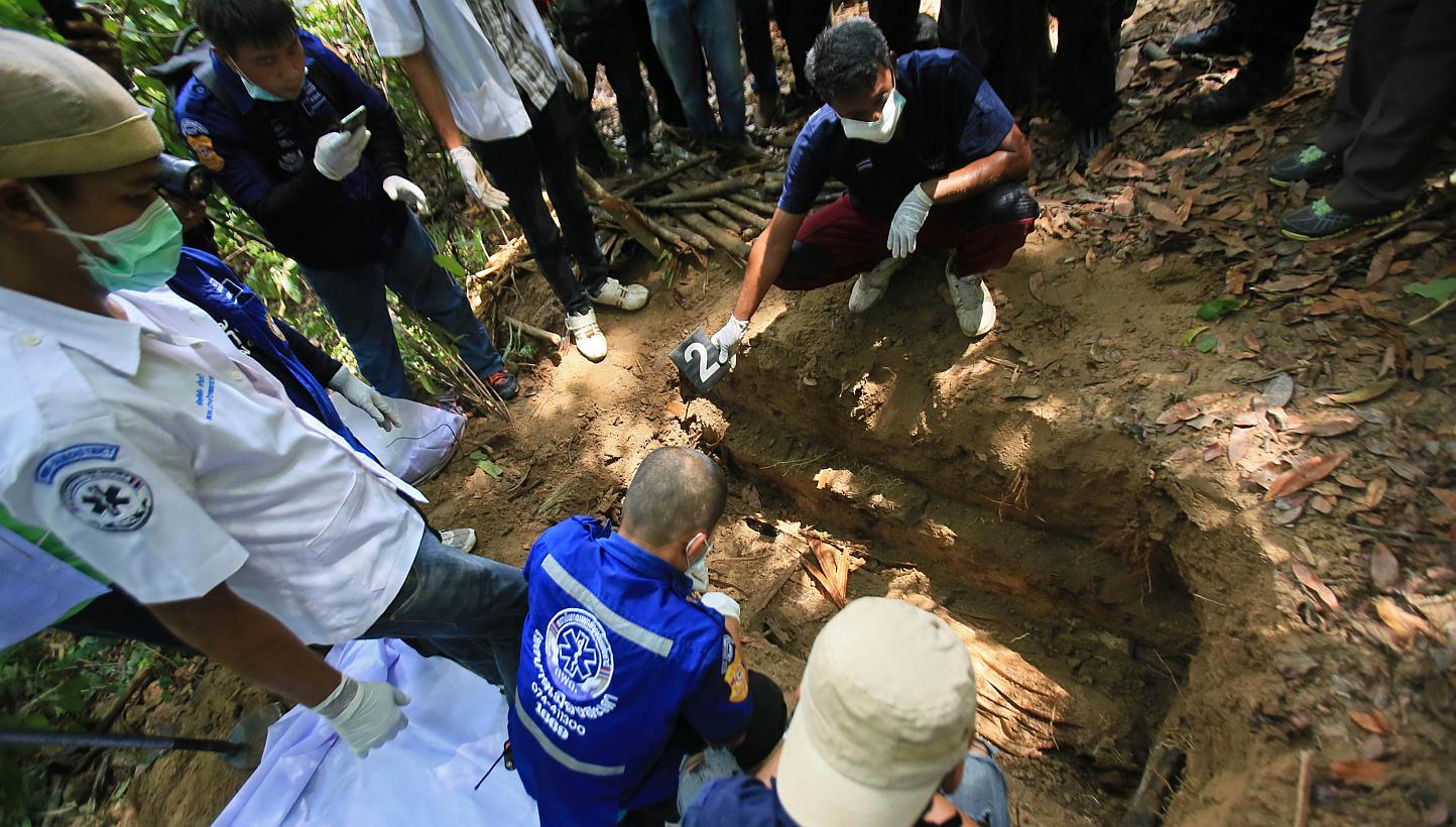 Rescue workers retrieve human remains from graves near the hillside site where shallow graves containing 26 bodies were found on May 1, close to the town of Padang Besar in the southern Thai province of Songkhla on May 13, 2015. -- PHOTO: AFP