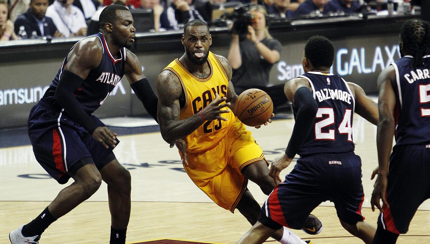 LeBron James (centre) of the Cleveland Cavaliers drives to the basket against (from left) Paul Millsap, Kent Bazemore, and DeMarre Carroll of the Atlanta Hawks during the second half of their NBA Eastern Conference Finals game 3 at Quicken Loans Aren