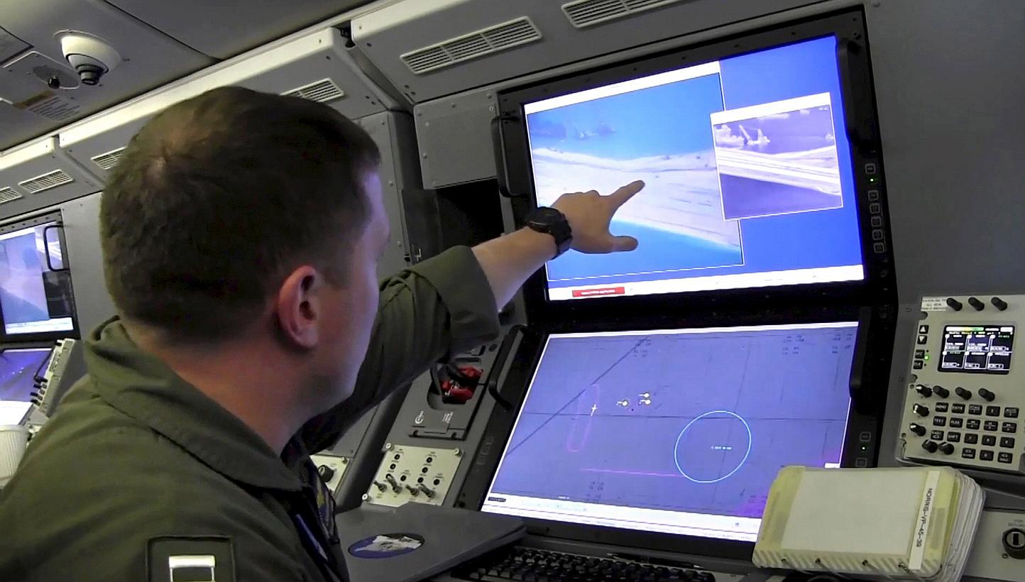 A U.S. Navy crewman aboard a P-8A Poseidon surveillance aircraft views a computer screen purportedly showing Chinese construction on the reclaimed land of Fiery Cross Reef in the disputed Spratly Islands in the South China Sea, in this file still ima