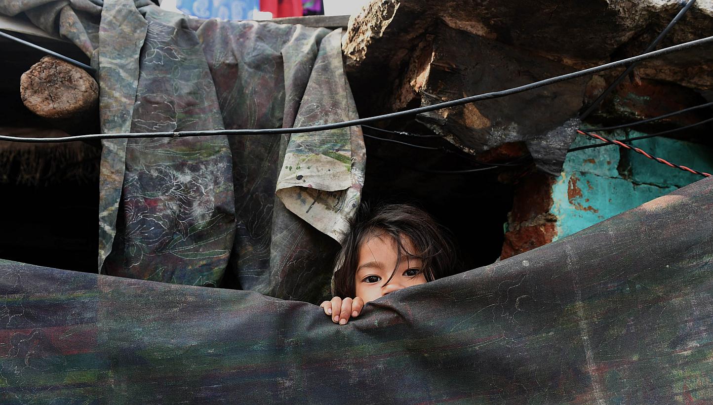 A young girl peeping out from her shanty in a slum in New Delhi on March 18, 2015. -- PHOTO: AFP