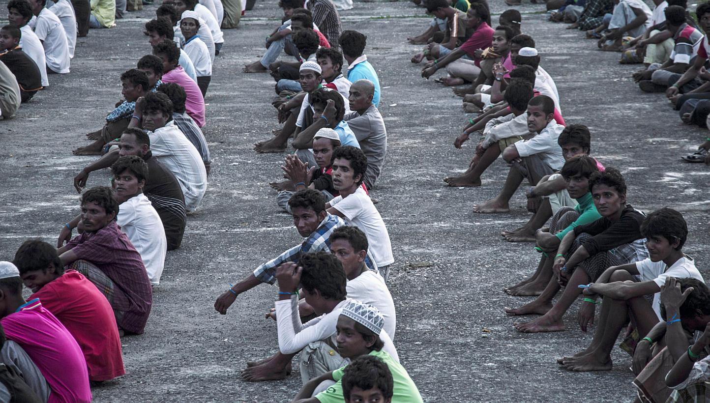 Ethnic Rohingya Muslim men from Myanmar sitting in lines at a confinement area situated amid a palm oil plantation at Bayeun, after more than 400 Rohingya migrants from Myanmar and Bangladesh were rescued by Indonesian fishermen off the coast of Aceh