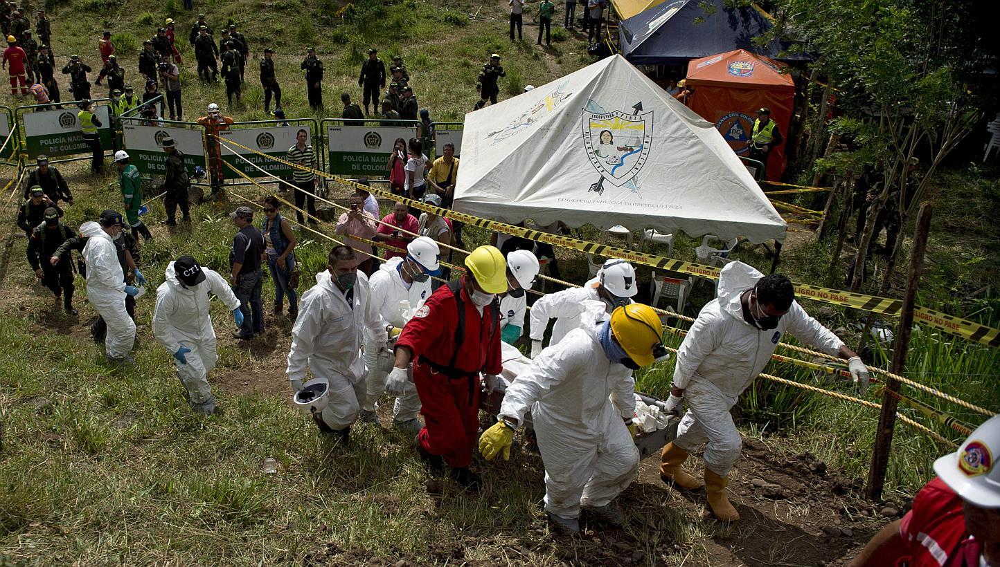 Forensic personnel and rescue workers carry the corpse of one of the fifteen miners who were trapped by the collapse of a gold mine, near the area of El Saibo, in Riosucio, Caldas department, Colombia, on May 15, 2015. -- PHOTO: AFP&nbsp;