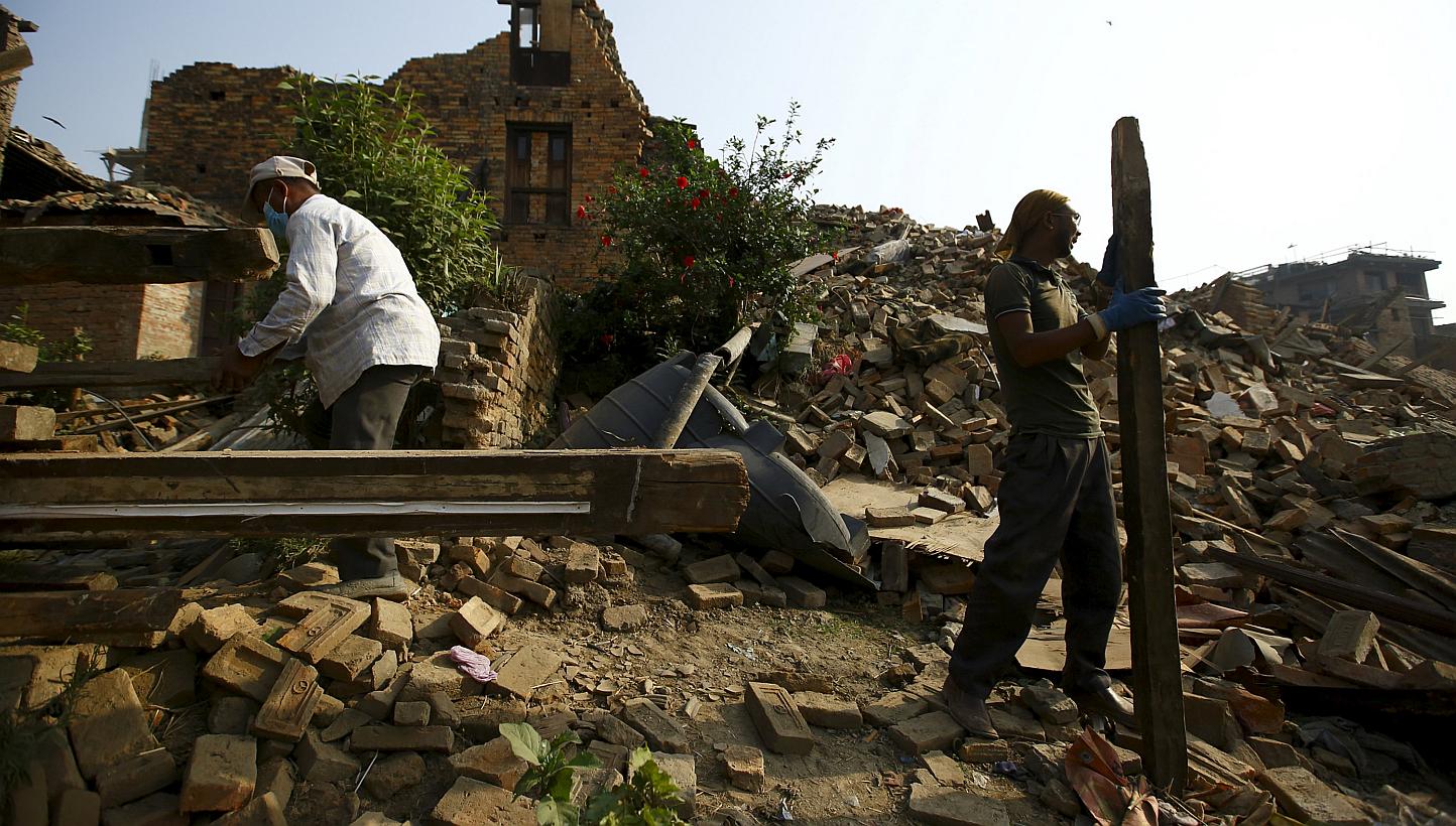 Two men working to clear debris from a collapsed house, a month after the April 25 earthquake in Kathmandu, Nepal on May 25, 2015. -- PHOTO: REUTERS