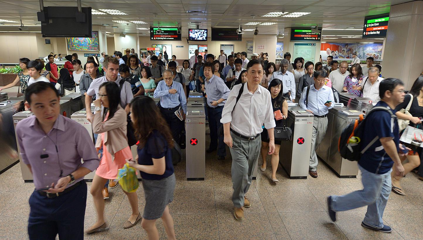 Commuters at Raffles Place MRT station. The Land Transport Authority is extending free pre-peak travel on the rail network for another year, to June 30, 2016. -- PHOTO: ST FILE