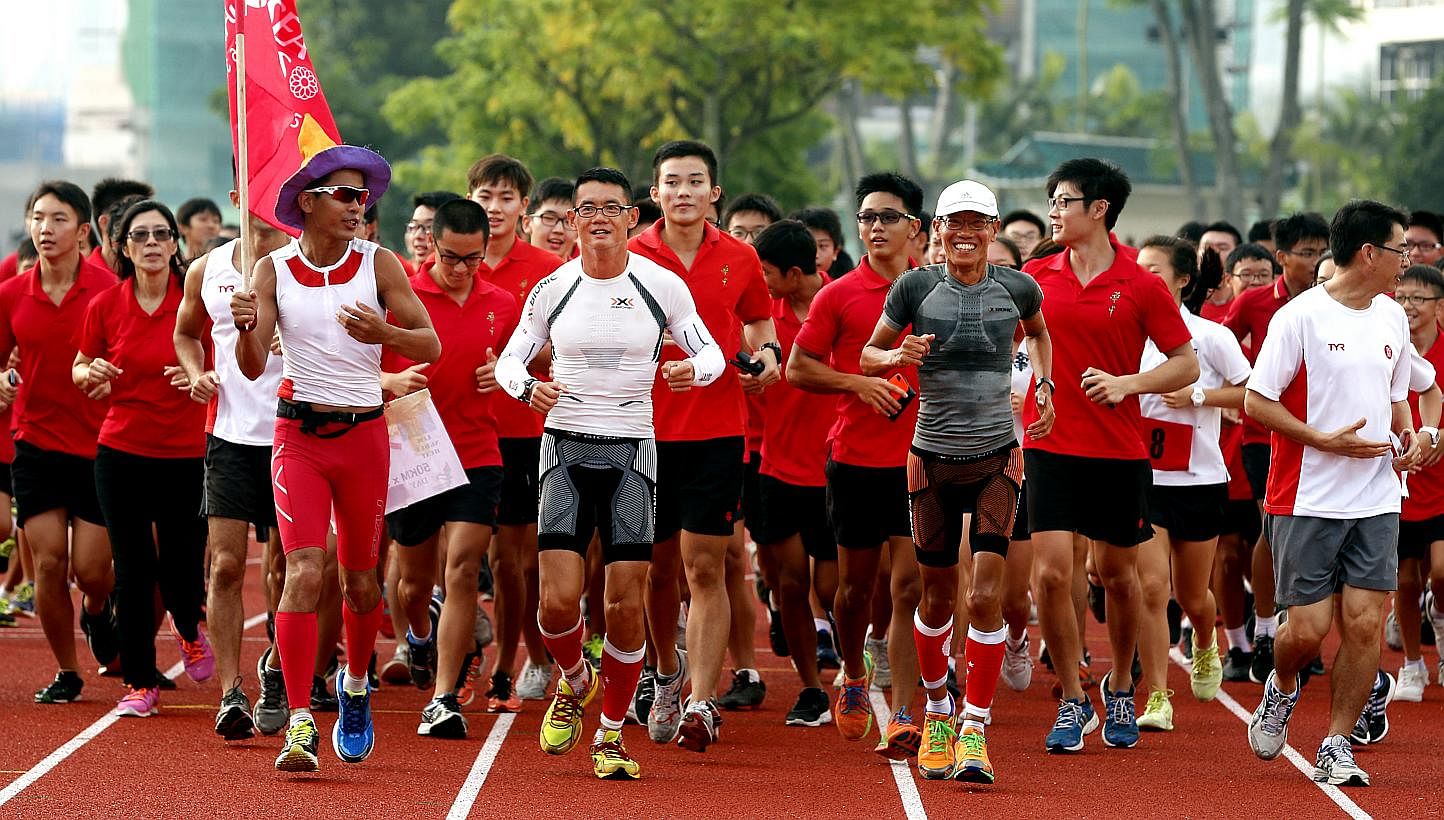 Pacer Gerrard Lin bearing the SEA Games flag as Mr Yong Yuen Cheng (centre, in white) and Mr Lim Nghee Huat (in grey) ran with students in Hwa Chong Institution yesterday.