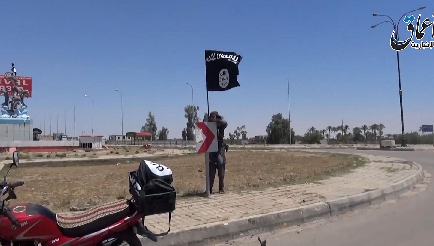 An image grab taken from a video uploaded on May 18, 2015 by Aamaq News Agency allegedly shows an Islamic State in Iraq and Syria (ISIS) fighter hanging the group's flag in a street of Ramadi. British researchers have reported that Western women who 