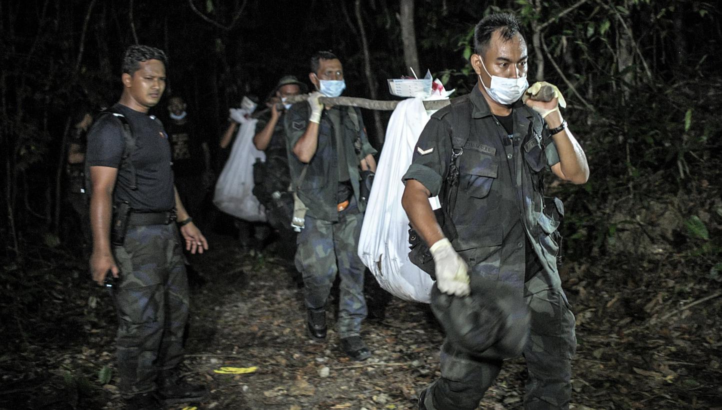 Royal Malaysian Police personnel carry exhumed human remains recovered from the jungle in the Malaysian northern state of Perlis, which borders Thailand, in Wang Kelian on May 28, 2015. -- PHOTO: AFP