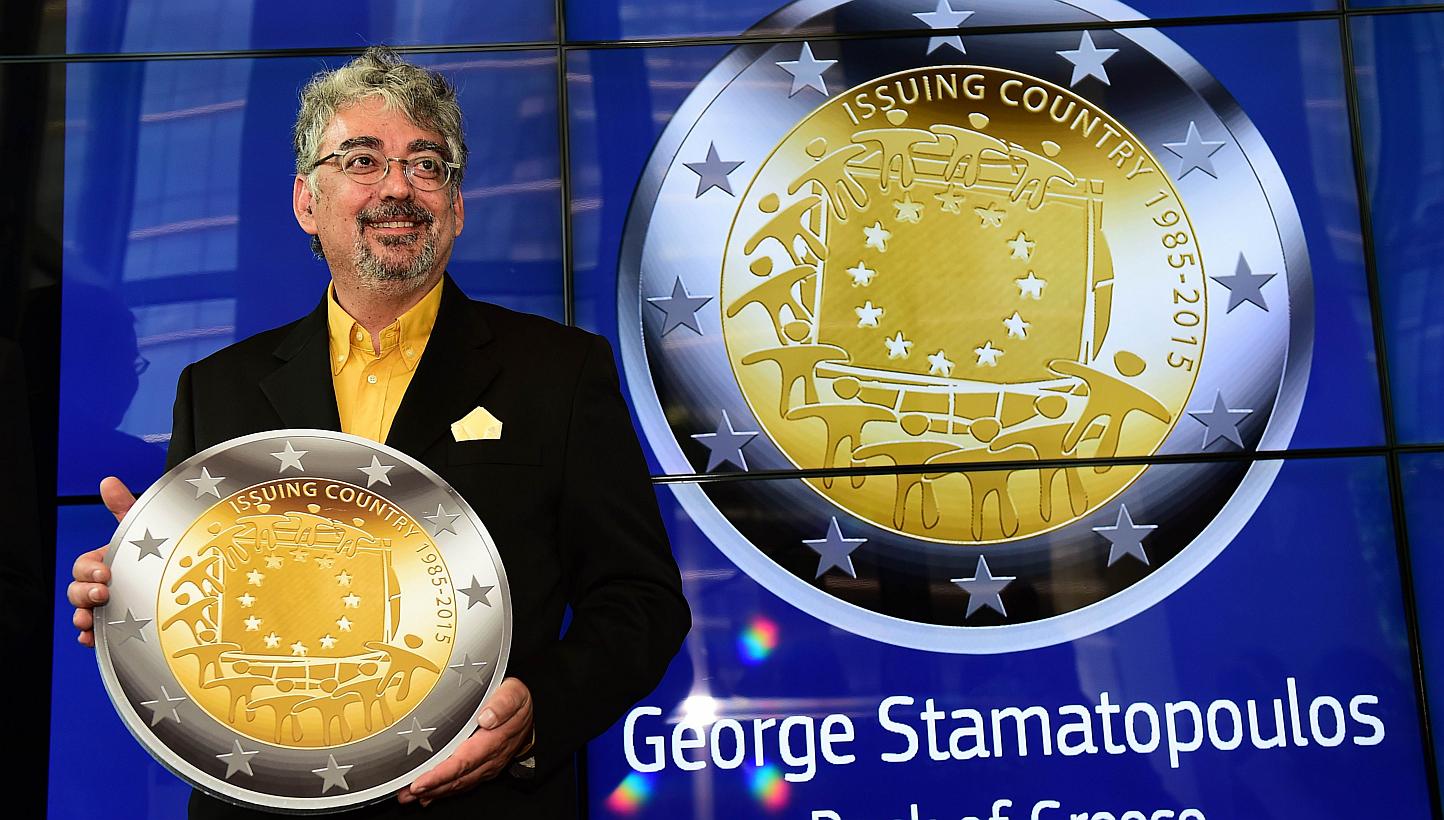 George Stamatopoulos, an engraver of the Bank of Greece, holds a replica of the commemorative two euro coin he designed, during a ceremony announcing that the coin design was chosen to mark the 30th anniversary of the adoption of the European flag as