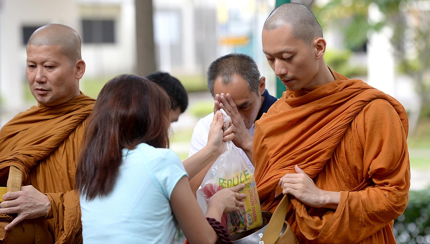 Venerable Goh Chun Kiang collecting cooked food from people at a food centre. The food is then distributed as lunch to the monks and lay people at Palelai Buddhist Temple. -- ST PHOTO: JAMIE KOH