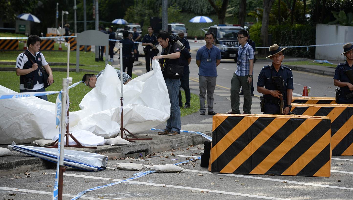 Members of the Singapore Police Force inspecting the site of a shooting at the junction of Orange Grove Road and Anderson Road, where a man was shot dead and two others were arrested after a car illegally bypassed a police vehicular checkpoint, early