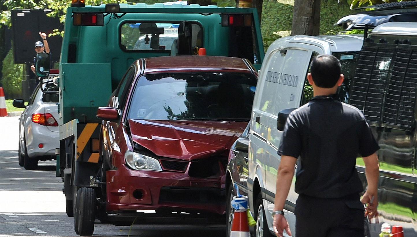 A damaged red car with a bullet hole on its windscreen is being towed away in Singapore near the Shangri-La hotel on May 31, 2015. Two passengers in the car that crashed through police barriers near the Shangri-la Hotel in the wee hours of Sunday wer