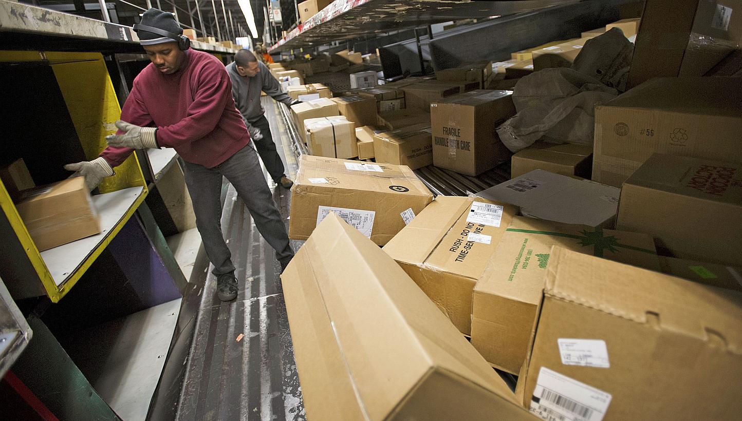 Employees sorting through packages at a United Parcel Service sorting facility in San Francisco, California, in 2012. Yet another app is launching in Singapore to match parcel senders with the nearest couriers. -- PHOTO: BLOOMBERG