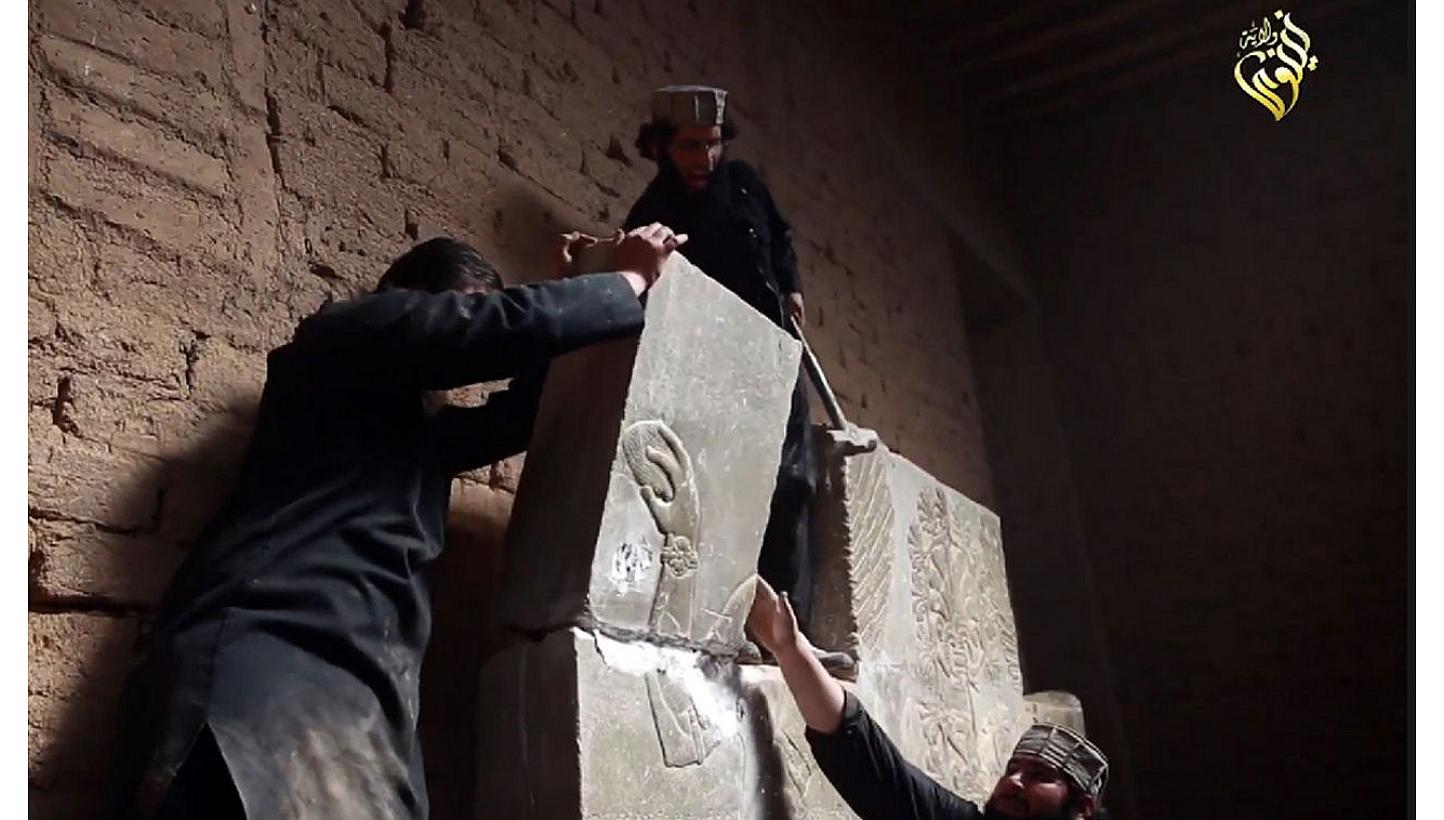 An image grab taken from a video on April 11, 2015, made available by Jihadist media outlet Welayat Nineveh allegedly shows members of the Islamic State in Iraq and Syria (ISIS) destroying a stoneslab with a sledgehammer at what they said was the anc