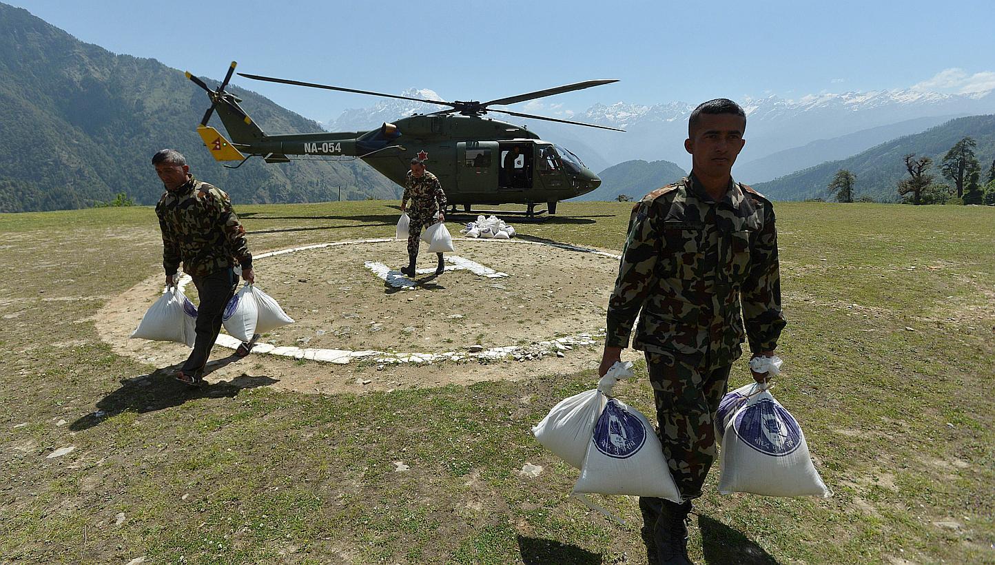 Nepalese Army soldiers run with parcels of food aid unloaded from a military transport helicopter at an army camp in the village of Rasuwa on May 28, 2015. A&nbsp;helicopter which had been delivering relief supplies crashed in Nepal's Sindhupalchowk 