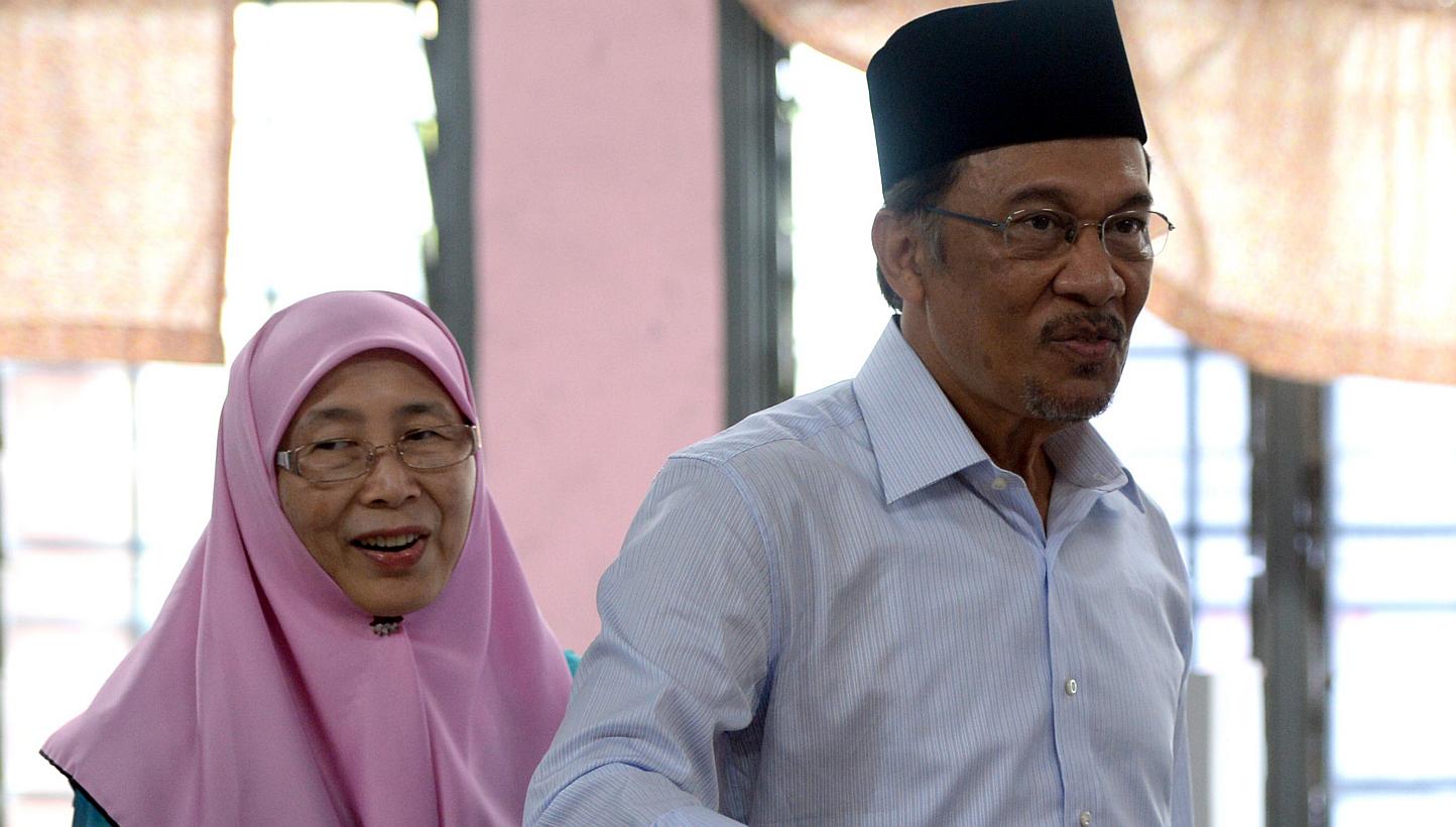 In this file photo taken on May 5, 2013, opposition leader Anwar Ibrahim (right), accompanied by his wife Wan Azizah, casts his vote at a polling station in Permatang Pauh, Penang. -- PHOTO: AFP