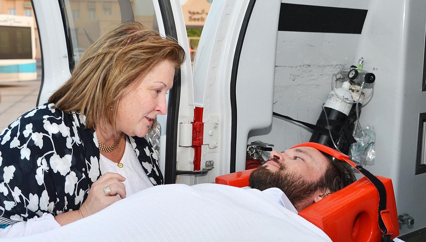 An unidentified woman speaks to an American, believed to have been held by Iran-backed Houthis, as he lays on a stretcher upon his arrival in Oman. An unidentified Singaporean was also released, and may have been among several people held by Iran-bac