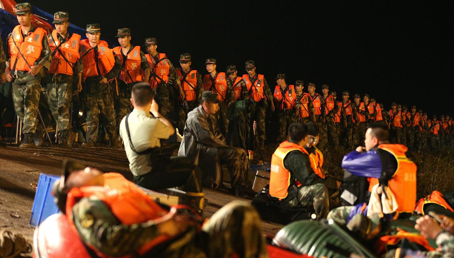Rescuers walk in a line along the bank side of the Yangtze River as they search for missing passengers of a capsized tourist ship in Jianli, Hubei province, China, on June 2, 2015. -- PHOTO: EPA&nbsp;