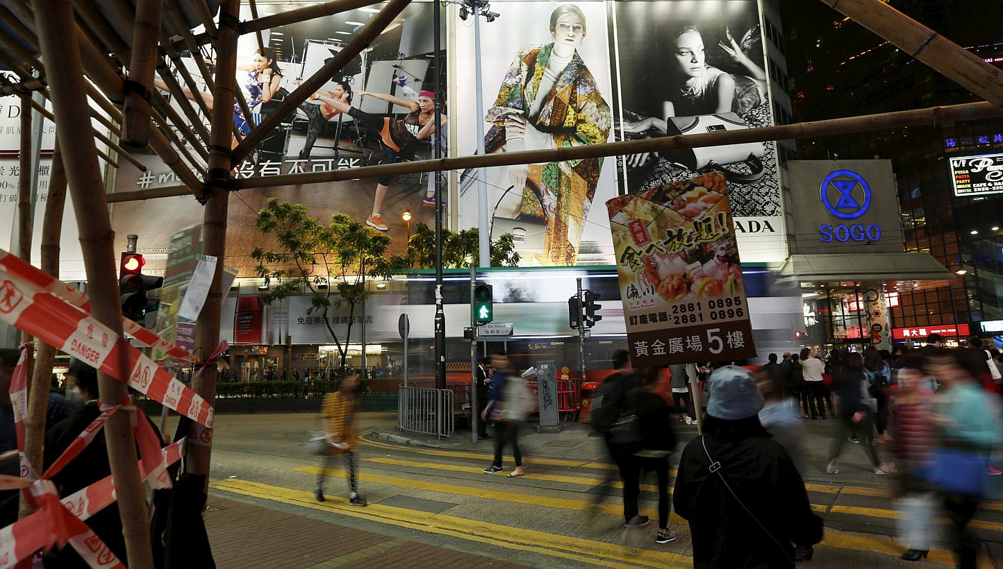 An attendant carries an advertisement of a Japanese restaurant as people cross at street at Causeway Bay shopping district in Hong Kong on March 26, 2015. -- PHOTO: REUTERS