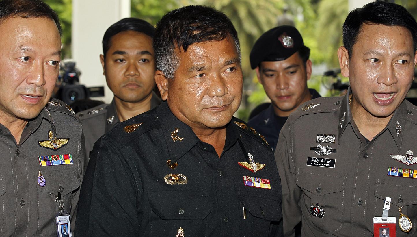 Thai Senior Army Advisor Lieutenant General Manas Kongpan (centre), who is allegedly involved in human trafficking of Rohingya migrants, is escorted by police officers as he turns himself in at the Royal Thai Police headquarters in Bangkok, Thailand,