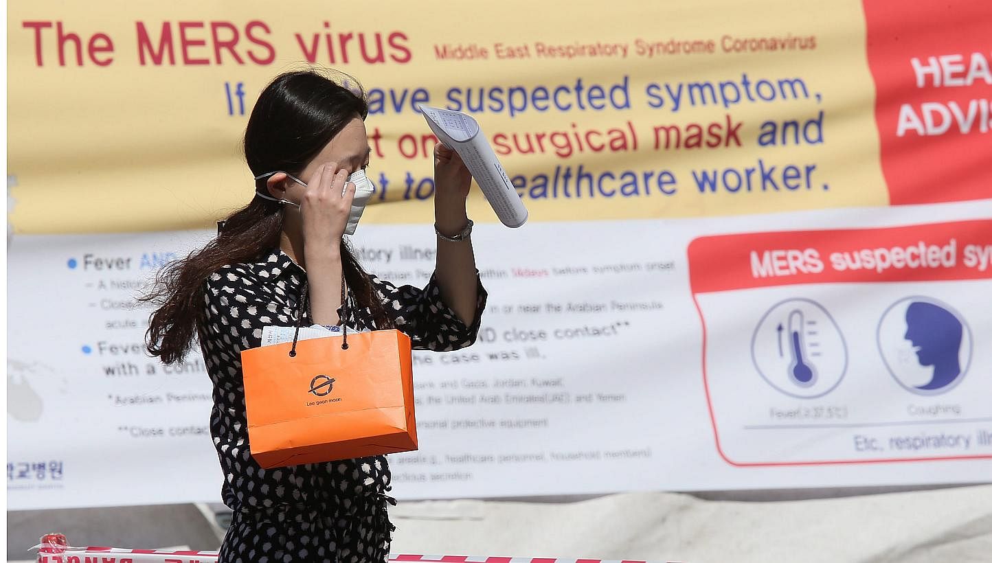 A woman wearing a facial mask walks past a facility at Seoul National University Hospital to examine temporarily quarantined people who could be infected with the Middle East Respiratory Syndrome (MERS),&nbsp;in Seoul, South Korea, on June 3, 2015. S