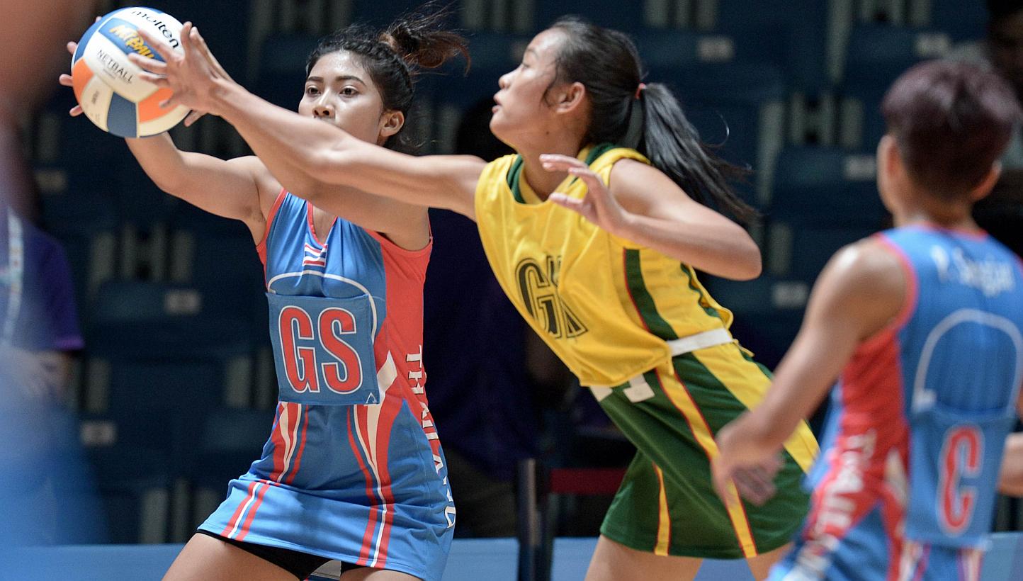 Thailand's Yada Boonkong (left) competes with Myanmar Mon Khin Aye (centre) during the women's netball preliminary round between Thailand and Myanmar at the 28th SEAgames 2015 in Singapore on June 3, 2015. -- PHOTO: AFP