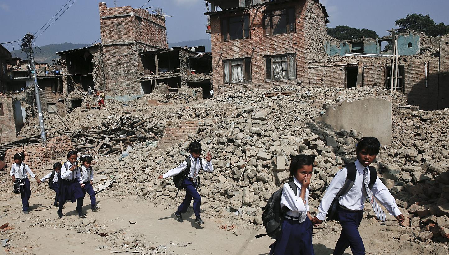 Nepalese children pass damaged houses in Bungmati, Kathmandu, Nepal on May 31, 2015, which were damaged by the earthquake on April 25, 2015. -- PHOTO: EPA