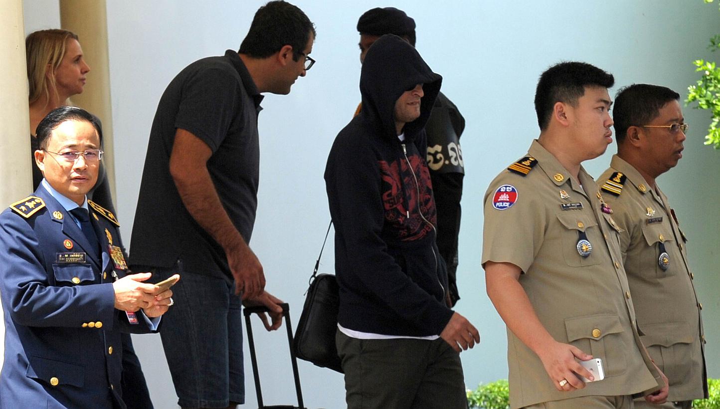 A refugee (third from right) held under Australian custody is escorted by Cambodian police following his arrival at the Phnom Penh International airport on June 4, 2015. -- PHOTO: AFP