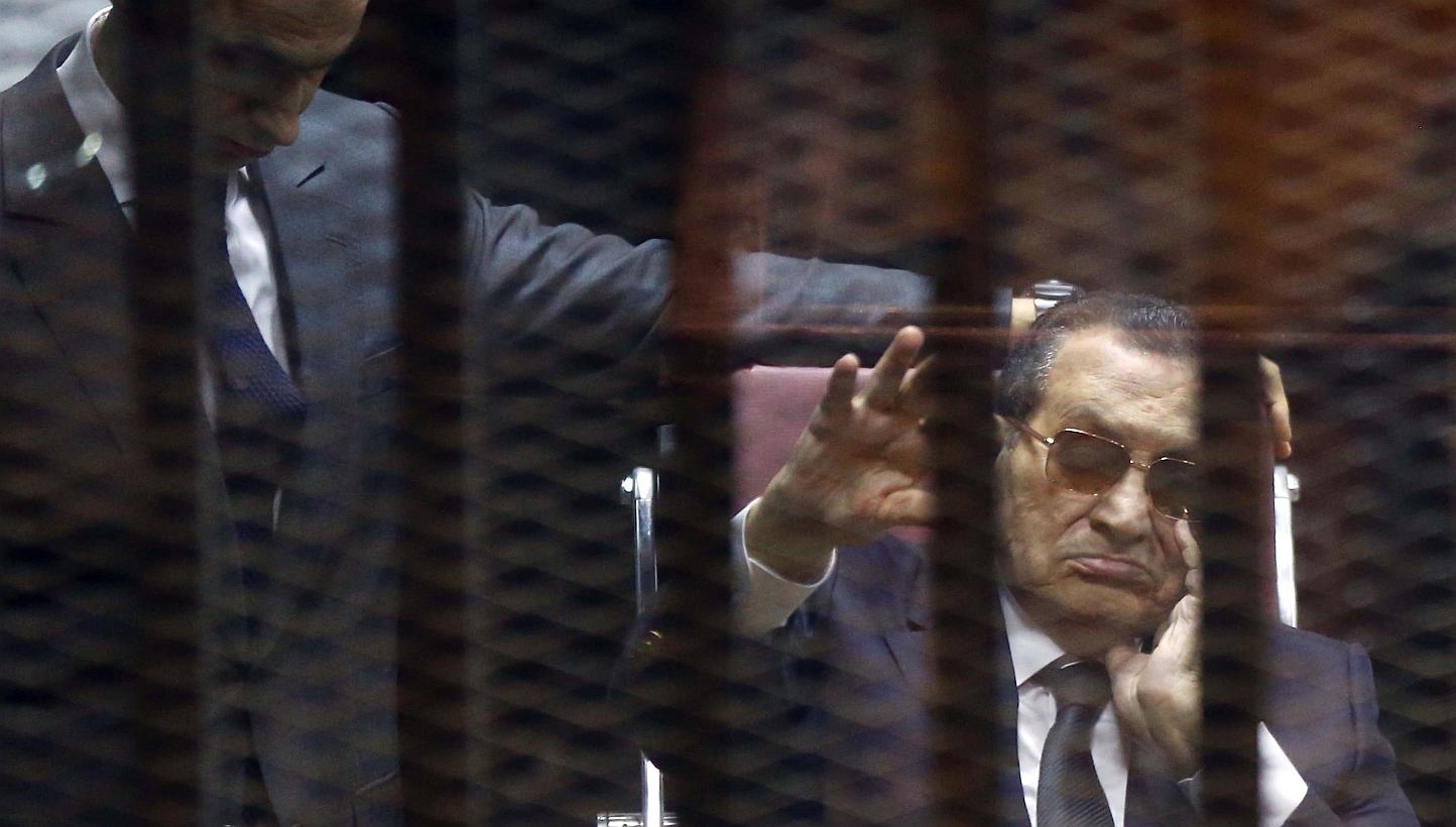 Ousted Egyptian president Hosni Mubarak (right) waves from the defendant’s cage next to one of his son's Gamal as they listen to the verdict in their hearing in a retrial for embezzlement in Cairo on May 9, 2015. Egypt's high court said on Thursday