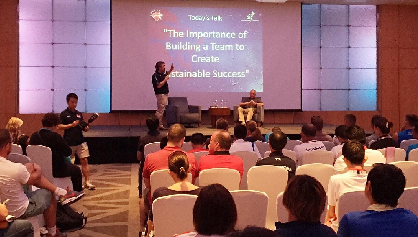 Singapore's national swim coach Sergio Lopez (standing) with guest speaker and three-time head coach of the US Olympics men's swimming team Eddie Reese (seated) on stage during the inaugural "Swim with Us by Sergio Lopez" coaching clinic at the Pan P