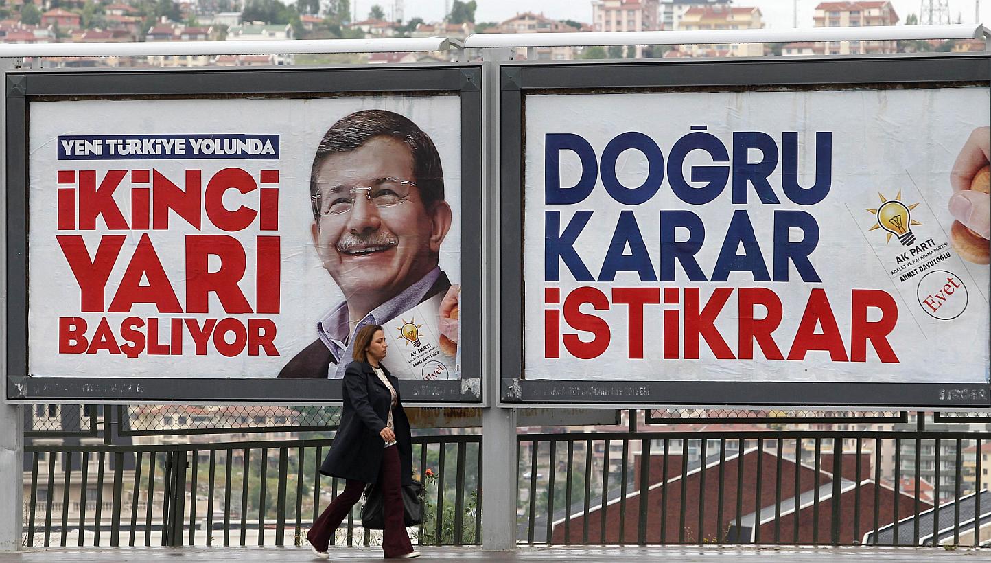 A woman walking in front of a campaign poster of Turkish Prime Minister Ahmet Davutoglu in Ankara Turkey, on June 4, 2015. -- PHOTO: AFP&nbsp;