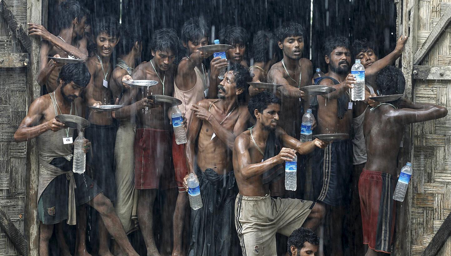 Migrants, who were found at sea on a boat, collecting rainwater during heavy rainfall at a temporary refugee camp near Kanyin Chaung jetty, outside Maungdaw township, northern Rakhine state in Myanmar, on June 4, 2015. -- PHOTO: REUTERS 