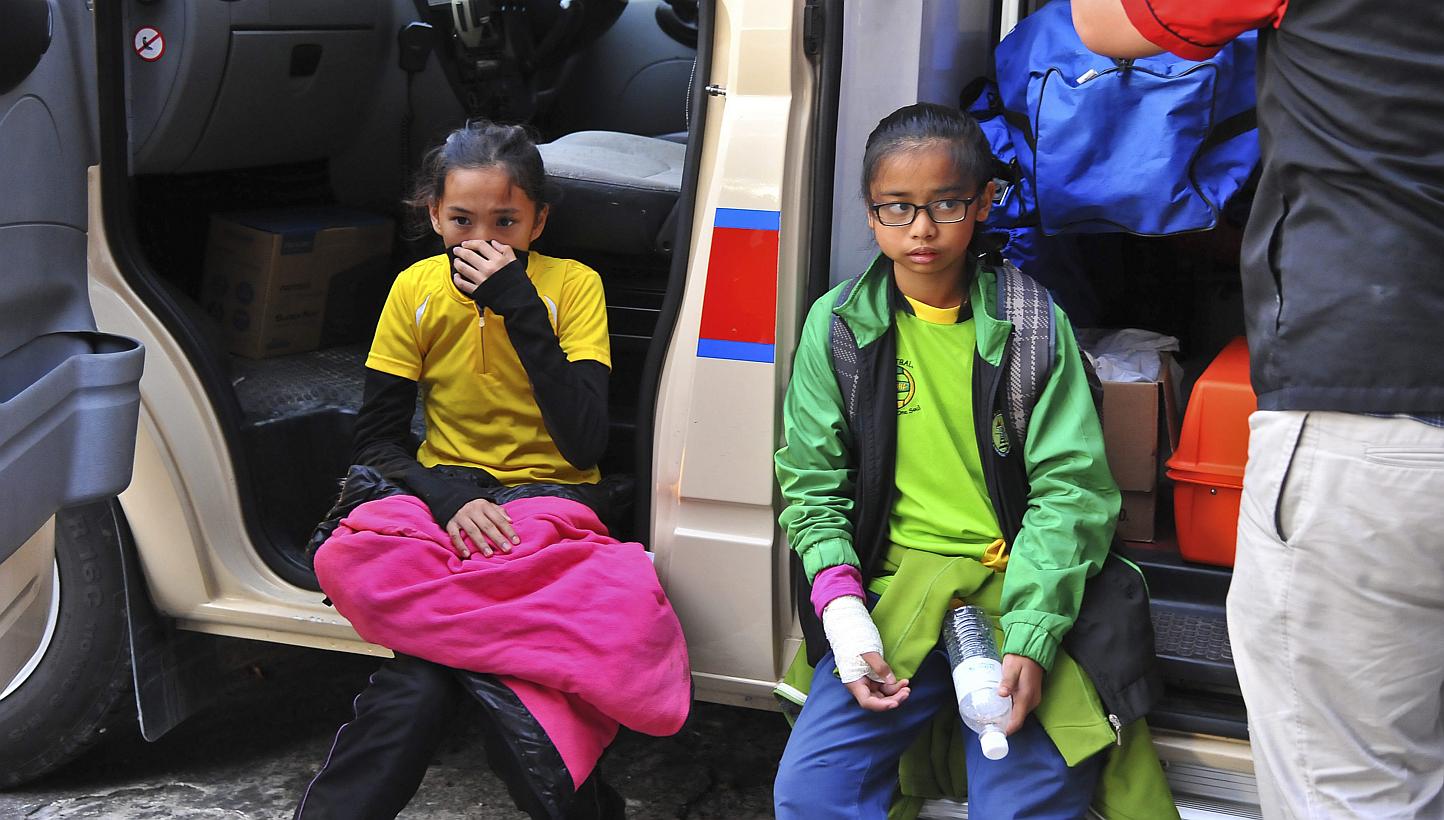A handout photograph made available by the Malaysian Information Ministry of Sabah on June 6, 2015 showing a victims from Singapore being examined outside the ambulance during a rescue mission for more than 130 climbers who were stranded on one of So