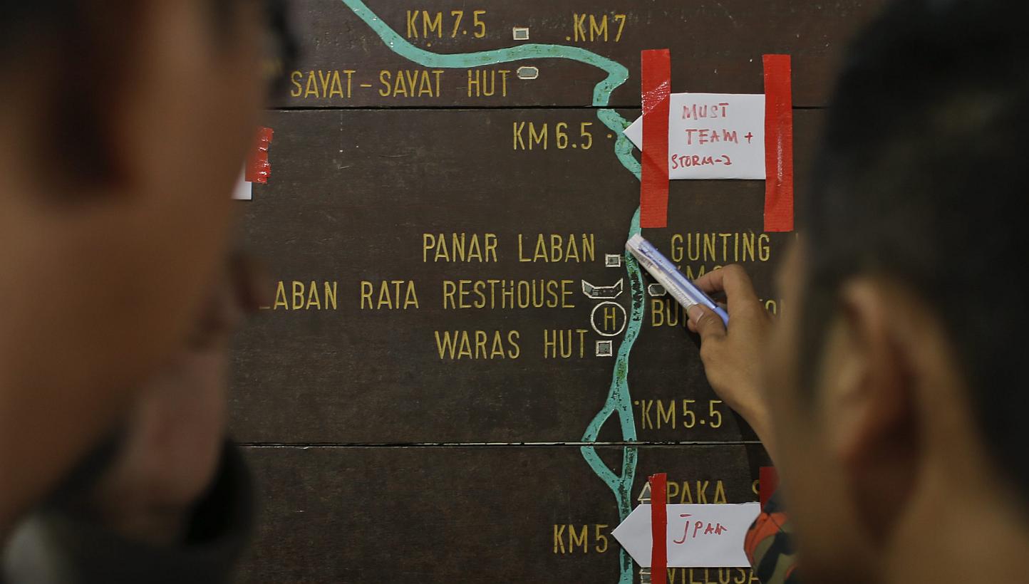 Malaysian rescue officials mark their current locations on the information board located on the way to Mount Kinabalu during a rescue mission for more than 130 climbers who were stranded on one of Southeast Asia's highest mountains after an earthquak