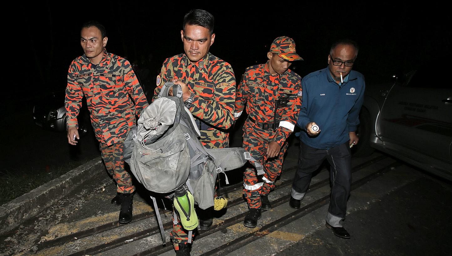 ABOVE: Emotions running high at Changi Airport yesterday as parents reunited with their children who had gone to Mount Kinabalu on a school trip. LEFT: Members of a Malaysian Fire and Rescue Department team with a bag containing part of a body retrie