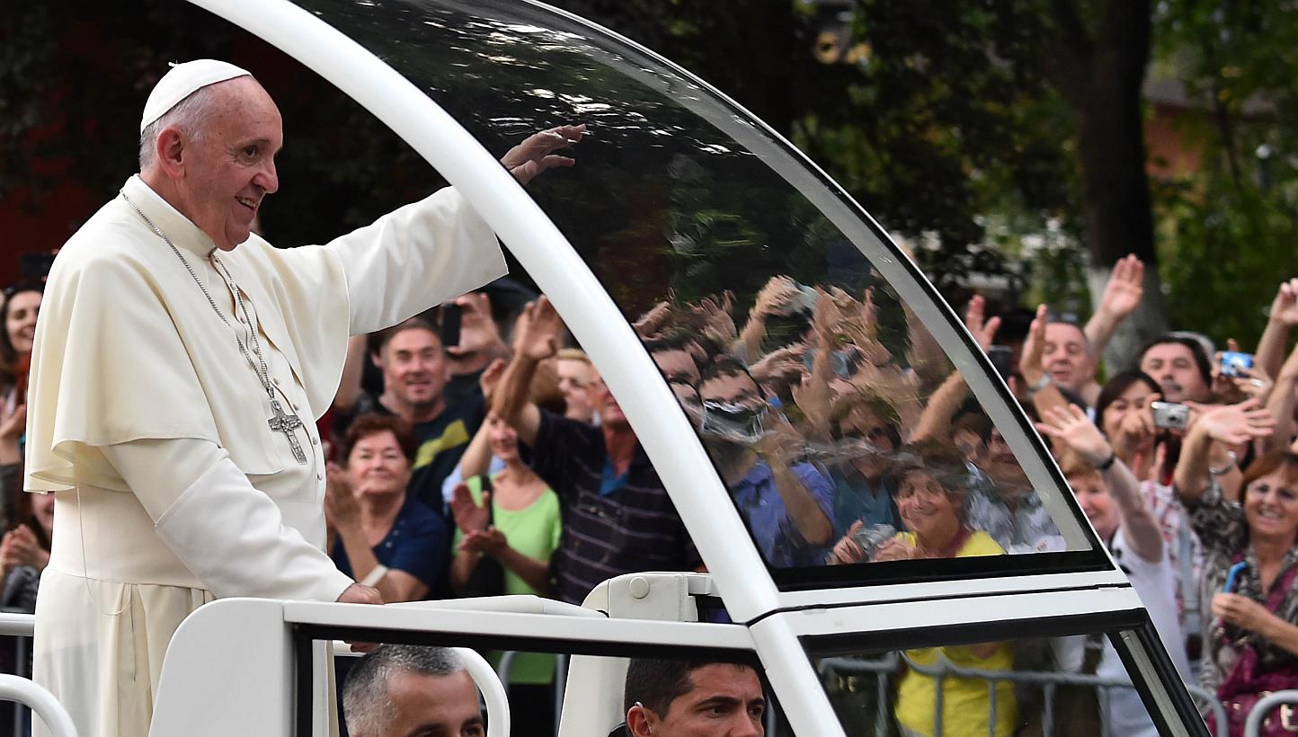 Pope Francis waves to the crowd from the popemobile on his way to an inter-religious meeting with the archbishop of Sarajevo, Cardinal Vinko Puljic, as part of a one day visit in Bosnia, on June 6, 2015 in Sarajevo. -- PHOTO: AFP