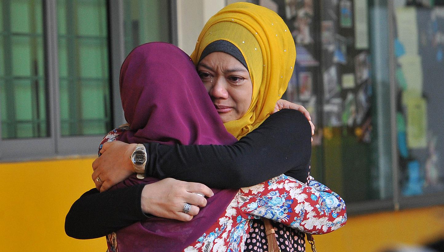 Family members of students from Tanjong Katong Primary School embrace in tears in memory of the victims from the school in an earthquake on Malaysia's Mount Kinabalu. -- PHOTO: AFP