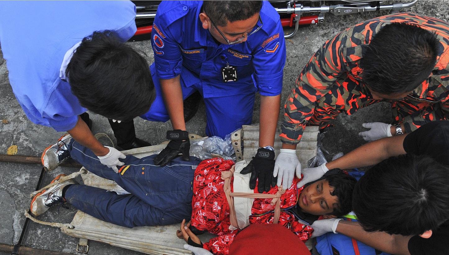 A Singapore victim being examined by personnel from Malaysia's Fire and Rescue Department and Civil Defence Department during a rescue mission in Kundasang on June 5, 2015. -- PHOTO: EPA