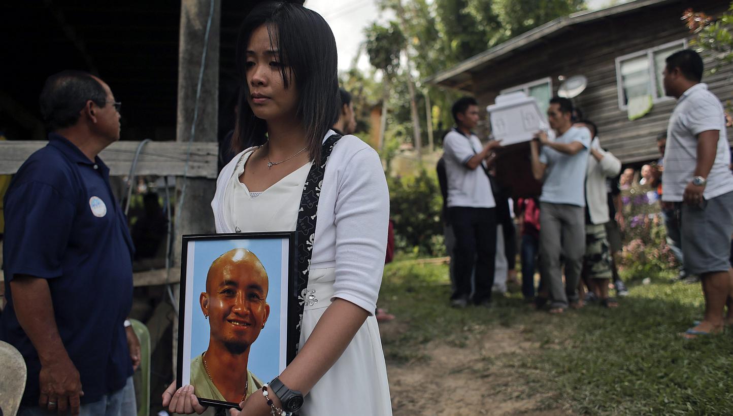 Jessica Sikta (second from left) holds a picture of her fiance Valerian Joannes, a 27-year-old tour guide who was among those killed in an earthquake which hit Sabah, during his funeral ceremony in Kundasang, Sabah, Malaysia, on June 8, 2015. -- PHOT