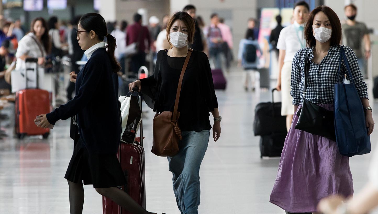 Tourists wearing face masks walk through Incheon International Airport in Incheon, South Korea, on Monday, June 8, 2015.&nbsp;To detect Mers-CoV cases early, Singapore will start temperature screening at air checkpoints for passengers arriving from S