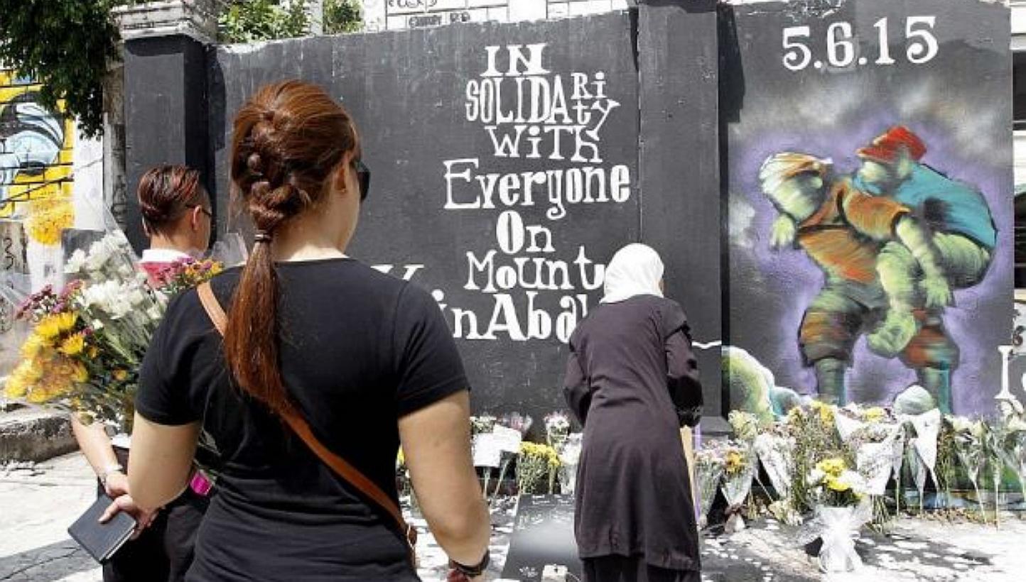 People paying their last respects to the victims of the earthquake at Mount Kinabalu at the graffiti corner of the old ruined colonial building in Kota Kinabalu. -- PHOTO: THE STAR/ASIA NEWS NETWORK