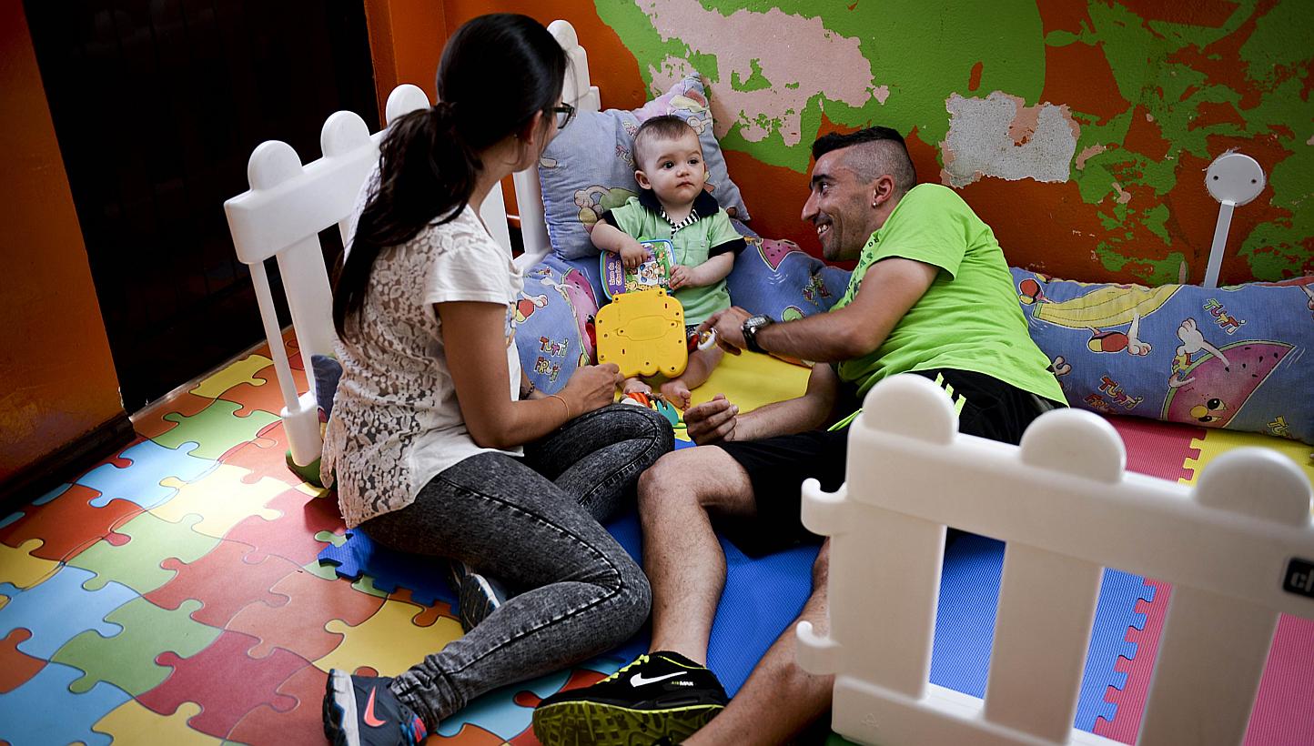 A file picture taken on May 14, 2015 shows Jessica (left) and her husband Antonio (right) playing with their child Martim born on August 8, 2014 at the kindergarten in Alcoutim, southern Portugal. The mayor of the small town of Alcoutim, in southern 