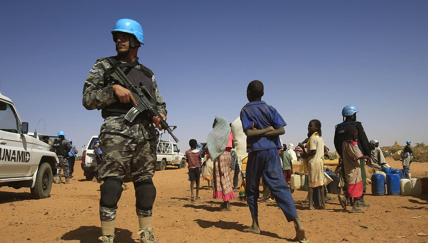 Sudanese people walk past members of the UN-African Union mission in Darfur (Unamid) at the Zam Zam camp for Internally Displaced People (IDP), North Darfur, on April 9, 2015. The UN&nbsp;on Wednesday, June 10, warned that violent attacks on internat