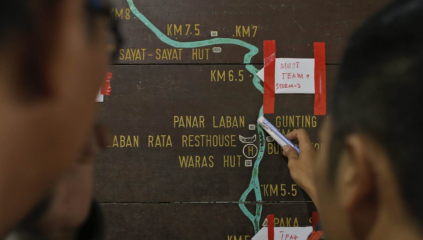 Malaysian rescue officials mark their current locations on the information board located on the way to Mount Kinabalu during a rescue mission on June 6, 2015. -- PHOTO: EPA