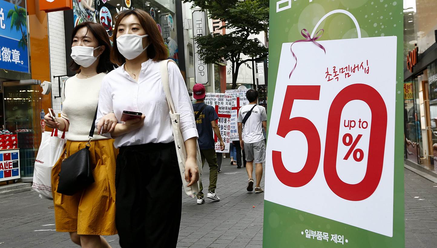 South Korean consumers wearing protective facial masks walk by a sale store in Myeong-dong, Seoul, South Korea on June 11, 2015. The outbreak of Middle East Respiratory Syndrome (Mers) in South Korea has become the biggest outside of Saudi Arabia. --
