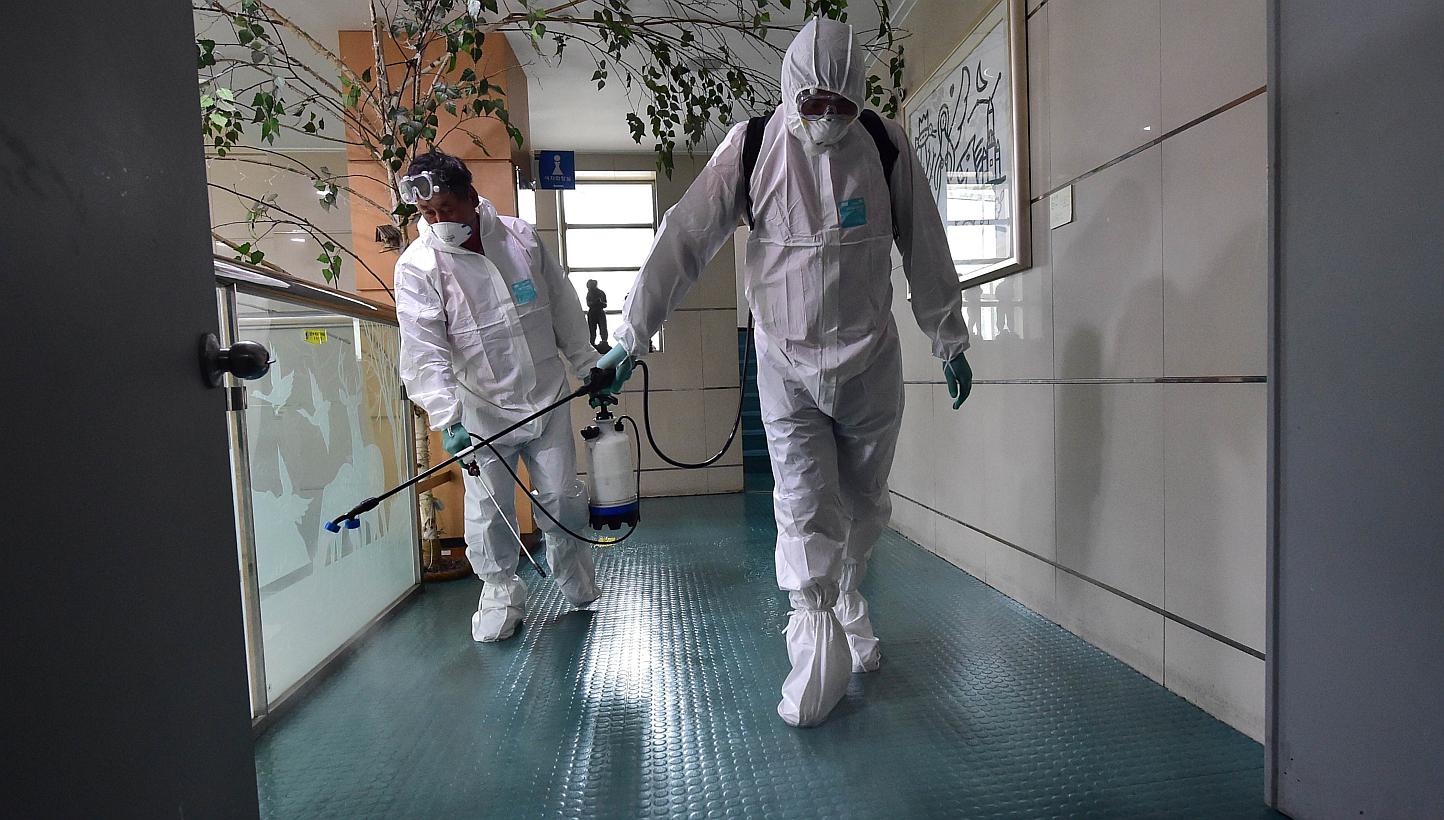South Korean health officials spraying an antiseptic solution while wearing protective gear in an art hall in Seoul on June 12, 2015. -- PHOTO: AFP
