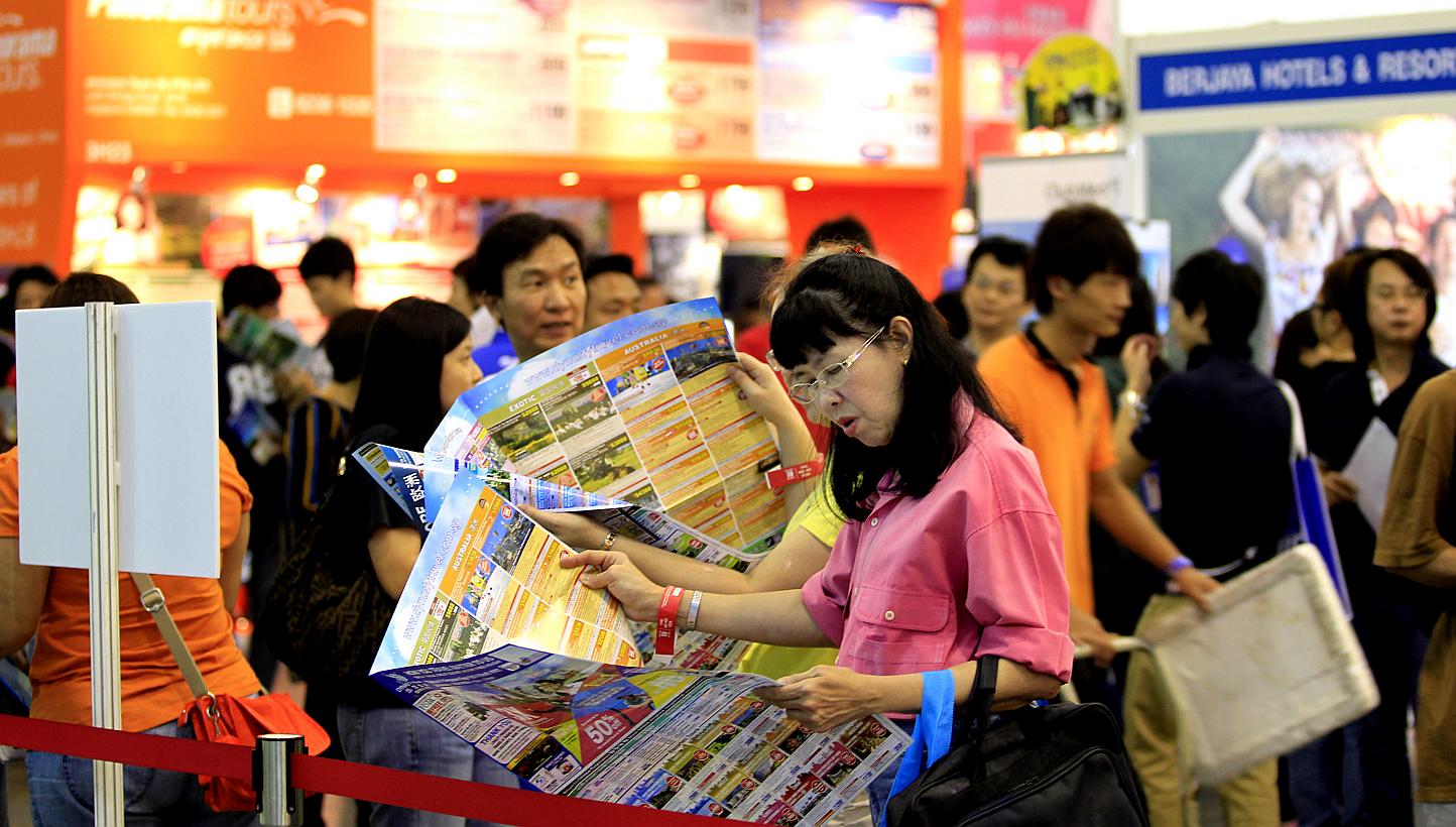 A woman looks through a tour brochure at a travel fair in Singapore. The Singapore Tourism Board announced a new licensing condition on Friday so that - from July 15 - all licensed travel agents will have to seek the decision of outbound leisure cust
