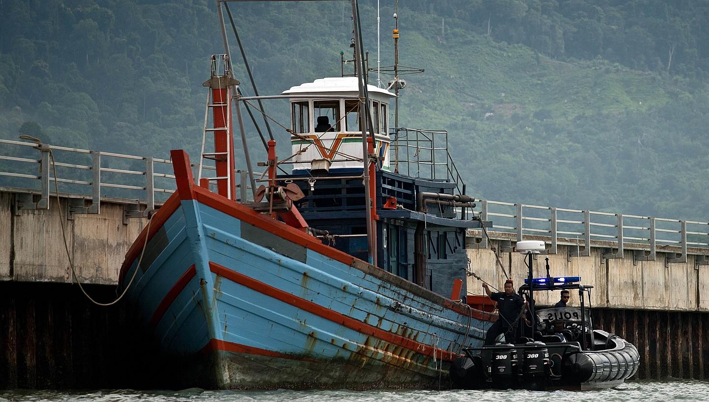 Malaysian maritime police inspecting a boat which carried illegal migrants in Langkawi on May 12, 2015. -- PHOTO: AFP