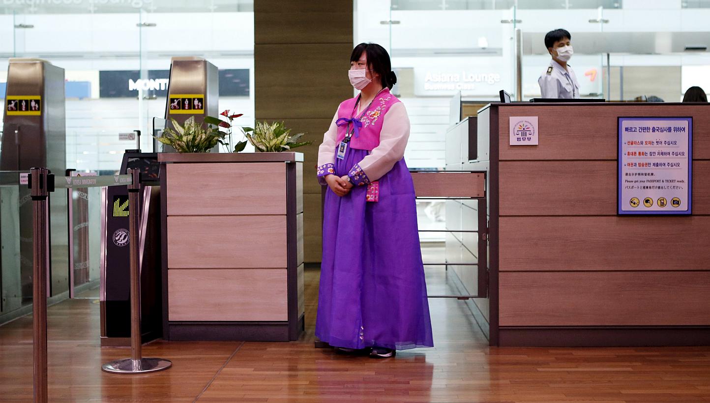 An employee dressed in a Hanbok traditional costume wears a mask to prevent contracting Middle East Respiratory Syndrome (Mers) as she stands in front of a check-in counter at the Incheon International Airport in Incheon, South Korea on June 14, 2015