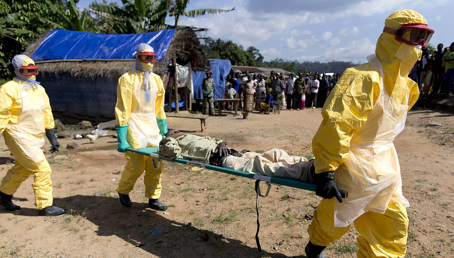 A file picture taken in Patrice near Macenta on Nov 21, 2014 shows health workers wearing protective suits carrying a patient suspected of having Ebola on their way to an Ebola treatment centre run by the French Red Cross. -- PHOTO: AFP