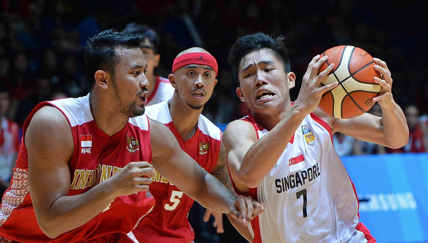 Singapore's Wu Qingde (right) attempting to fend off Indonesia's Adhipratama Putra in their men's basketball semi-final at the OCBC Arena on June 14, 2015. -- ST PHOTO: CHONG JUN LIANG &nbsp;
